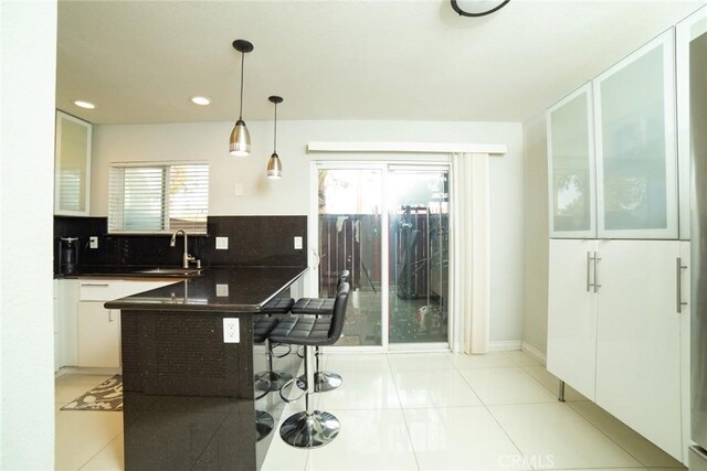 1745 N Winery Ave Unit 102, Fresno, CA 93703 - kitchen with a breakfast bar area, a peninsula, a sink, decorative backsplash, and dark countertops