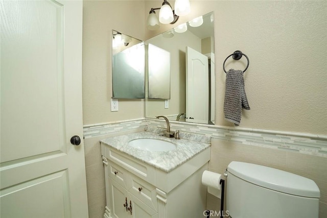 1745 N Winery Ave Unit 102, Fresno, CA 93703 - bathroom featuring a wainscoted wall, toilet, tile walls, and vanity