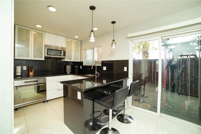 1745 N Winery Ave Unit 102, Fresno, CA 93703 - kitchen with light tile patterned flooring, a sink, white cabinets, appliances with stainless steel finishes, and modern cabinets