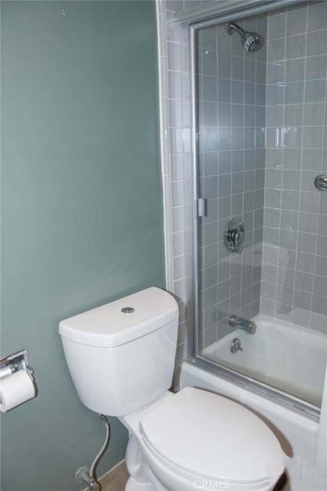 bathroom featuring bath / shower combo with glass door and toilet