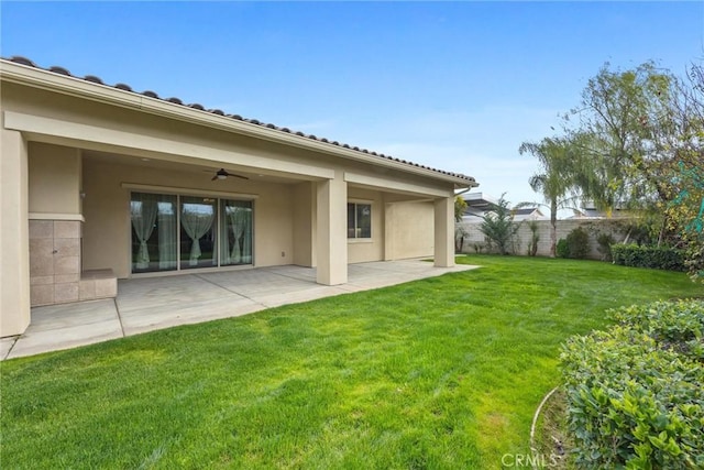 back of property with a lawn, a patio, and ceiling fan