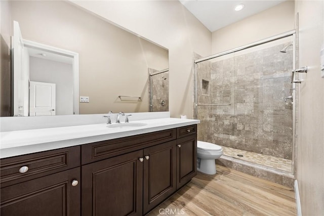 bathroom with vanity, wood-type flooring, a tile shower, and toilet