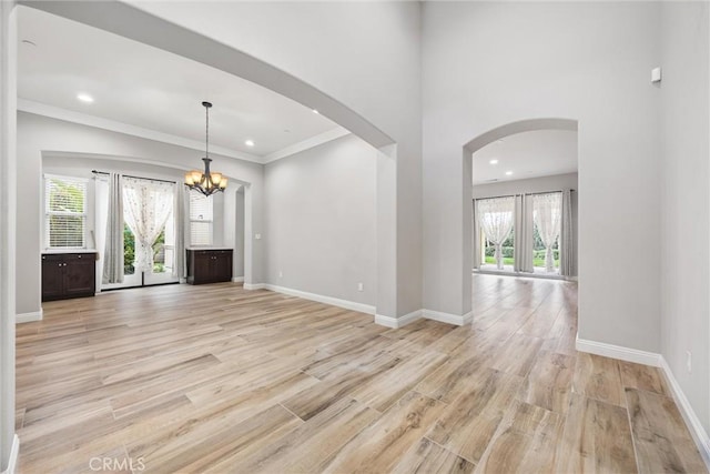 interior space featuring a notable chandelier, light hardwood / wood-style flooring, ornamental molding, and plenty of natural light