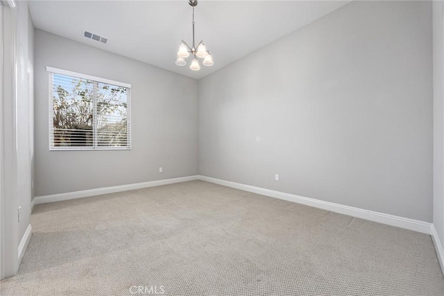 carpeted empty room featuring a chandelier