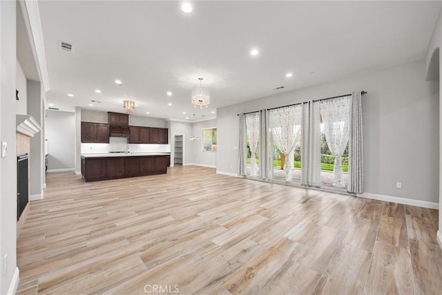 unfurnished living room with sink, light hardwood / wood-style flooring, and a chandelier