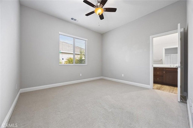 unfurnished bedroom with connected bathroom, light colored carpet, and ceiling fan