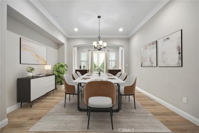 dining space featuring an inviting chandelier, ornamental molding, and light hardwood / wood-style floors