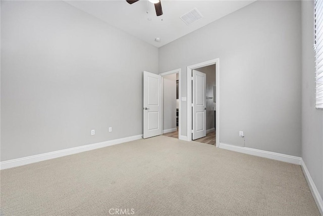 unfurnished bedroom featuring connected bathroom, light colored carpet, and ceiling fan