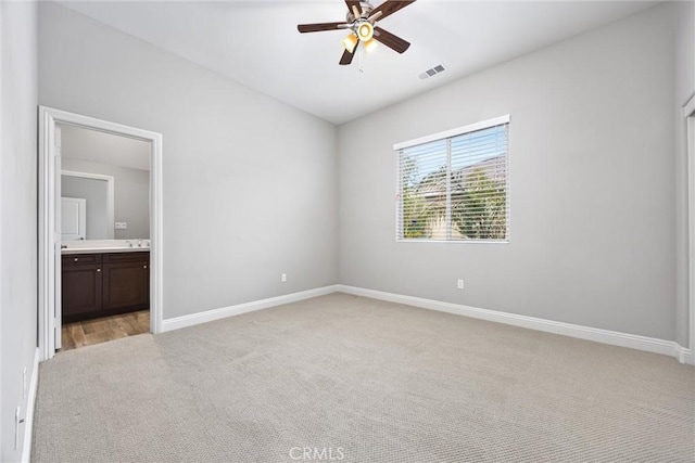 unfurnished bedroom featuring ceiling fan, light colored carpet, and ensuite bathroom