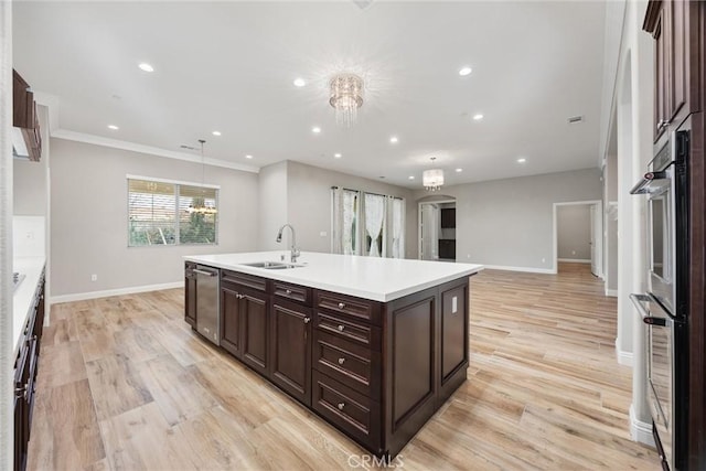 kitchen featuring sink, light hardwood / wood-style flooring, a kitchen island with sink, double oven, and an inviting chandelier