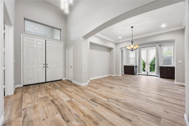 entryway featuring ornamental molding, a high ceiling, light hardwood / wood-style flooring, and a notable chandelier