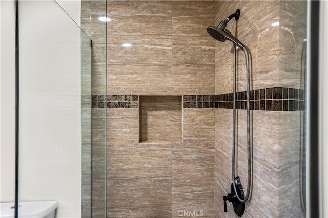 interior details featuring toilet and tiled shower