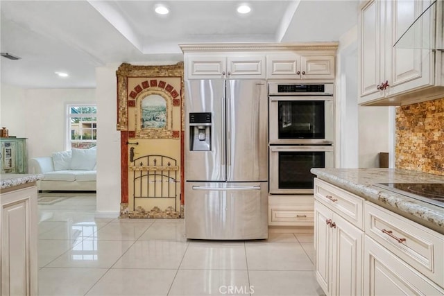 kitchen featuring light stone counters, light tile patterned floors, tasteful backsplash, and appliances with stainless steel finishes