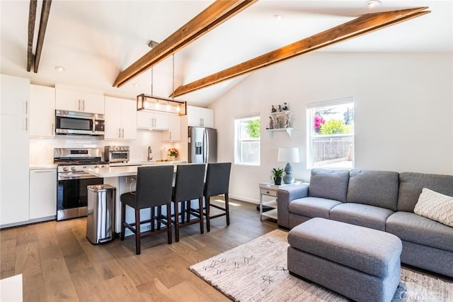 kitchen featuring a kitchen bar, hanging light fixtures, stainless steel appliances, decorative backsplash, and white cabinets