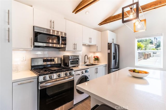 kitchen featuring washer / dryer, sink, vaulted ceiling with beams, white cabinets, and stainless steel appliances