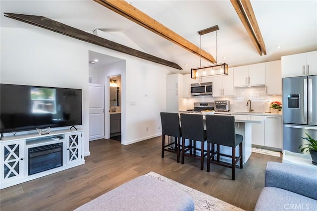 kitchen featuring a kitchen island, appliances with stainless steel finishes, pendant lighting, white cabinets, and a kitchen bar