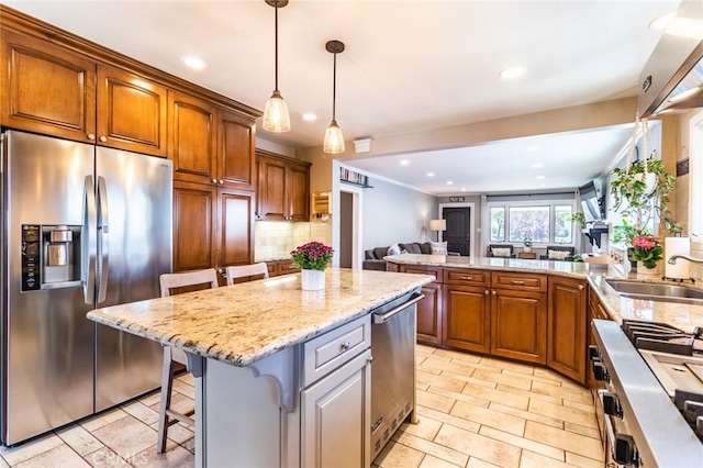 kitchen with appliances with stainless steel finishes, pendant lighting, sink, a breakfast bar area, and a center island