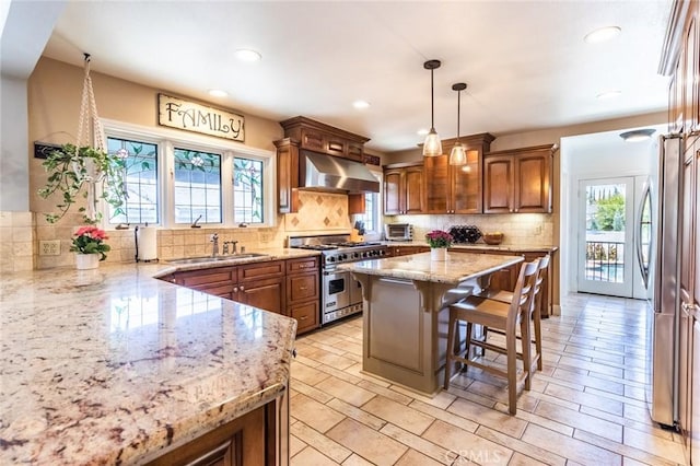 kitchen featuring appliances with stainless steel finishes, decorative light fixtures, a breakfast bar area, exhaust hood, and light stone counters