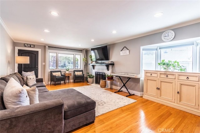 living room featuring crown molding, a brick fireplace, and light wood-type flooring