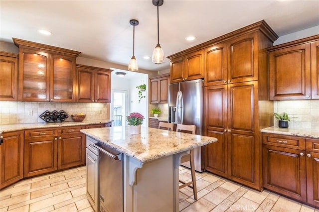 kitchen with pendant lighting, appliances with stainless steel finishes, a kitchen bar, tasteful backsplash, and a kitchen island