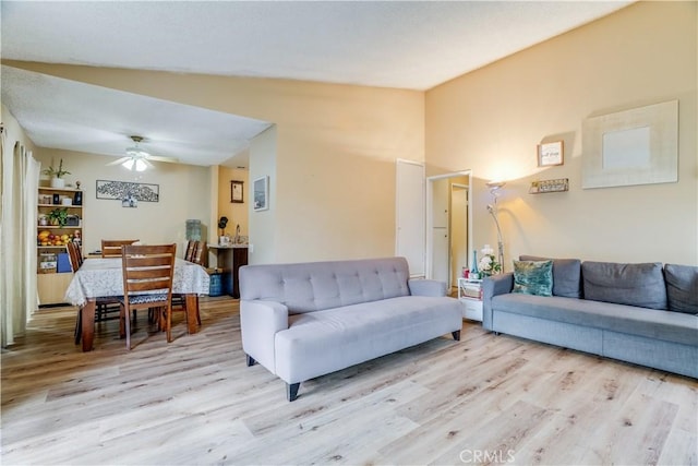 living room with vaulted ceiling, ceiling fan, and light wood-type flooring