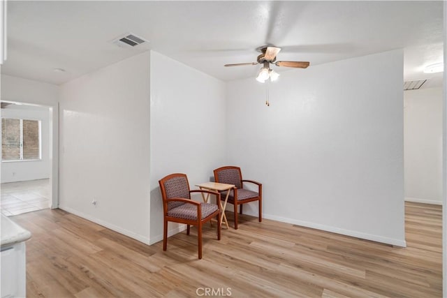 sitting room with ceiling fan and light wood-type flooring