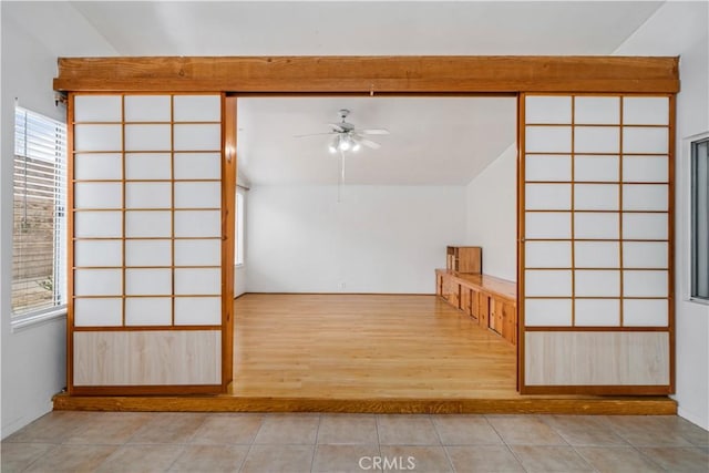 empty room featuring vaulted ceiling, light tile patterned floors, and ceiling fan