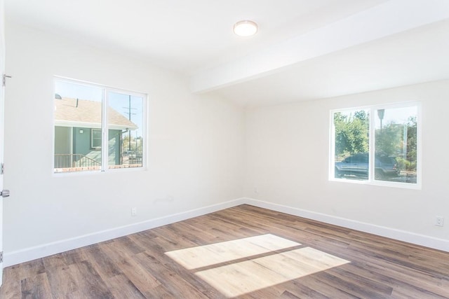 spare room with a wealth of natural light, beamed ceiling, and wood-type flooring