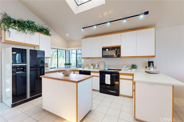 kitchen with white cabinets, a peninsula, vaulted ceiling with skylight, black appliances, and light tile patterned floors