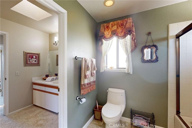 bathroom with toilet, vanity, a skylight, and baseboards