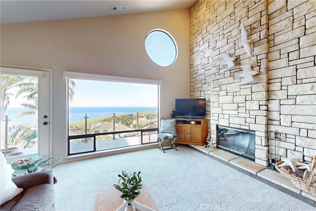 carpeted living area featuring a towering ceiling, a fireplace, and visible vents