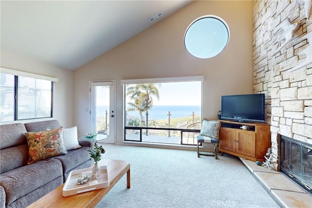 living room with carpet floors, a stone fireplace, plenty of natural light, and visible vents