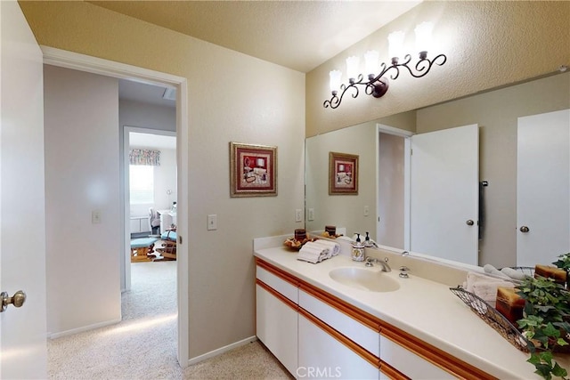 bathroom with vanity, baseboards, and a textured ceiling