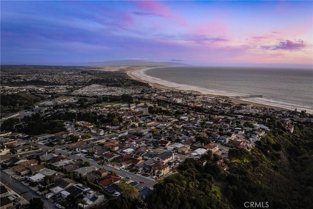 aerial view at dusk with a water view and a residential view