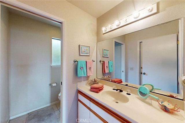 bathroom with toilet, vanity, and baseboards