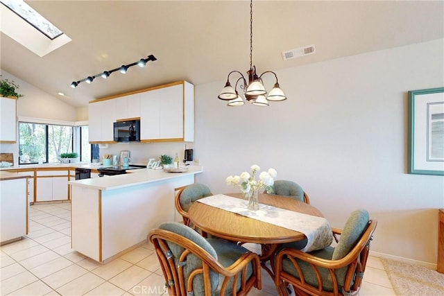 dining area with light tile patterned flooring, visible vents, an inviting chandelier, and lofted ceiling with skylight
