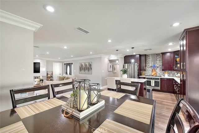 dining room with ornamental molding and light wood-type flooring