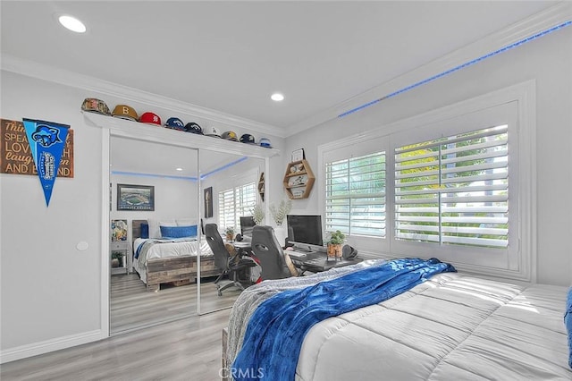 bedroom with ornamental molding, wood-type flooring, and a closet