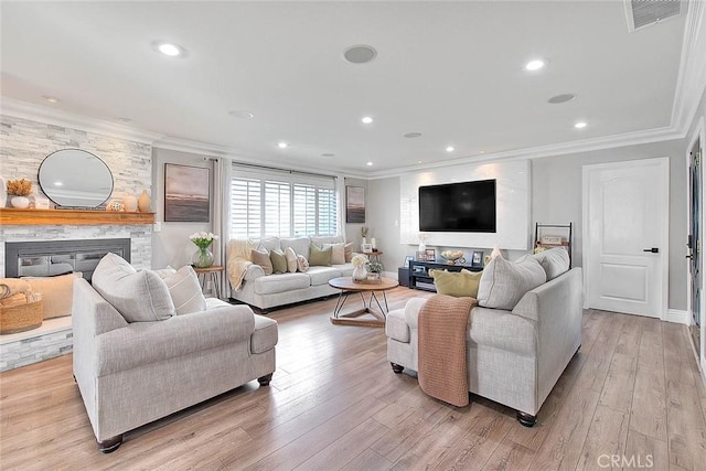 living room with ornamental molding, a stone fireplace, and light wood-type flooring