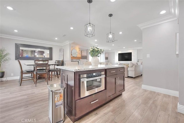 kitchen with crown molding, dark brown cabinets, hanging light fixtures, a kitchen island, and oven