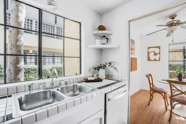 kitchen with sink, white cabinetry, tile counters, a healthy amount of sunlight, and stainless steel dishwasher