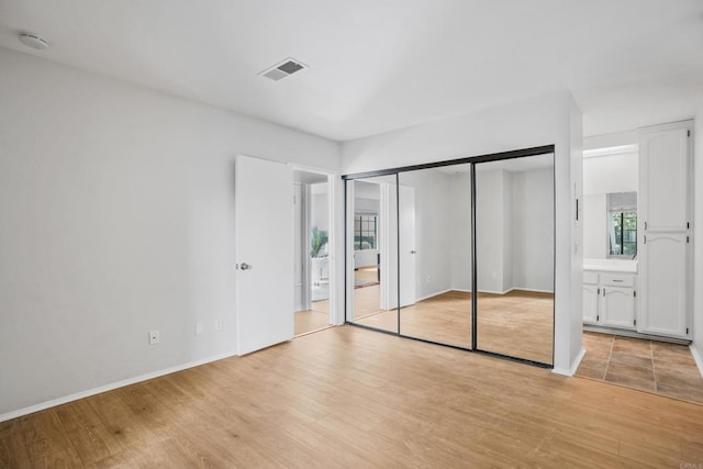 unfurnished bedroom with connected bathroom and light hardwood / wood-style floors