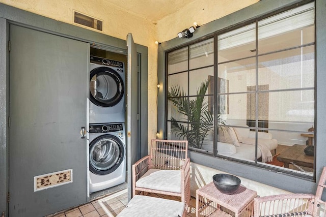 laundry room with light tile patterned flooring and stacked washer / dryer