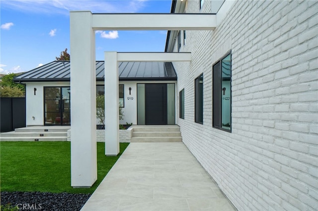 doorway to property with a standing seam roof, metal roof, and a lawn