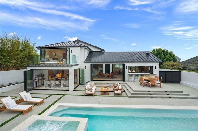 rear view of house featuring metal roof, a balcony, outdoor dining space, a standing seam roof, and a patio area