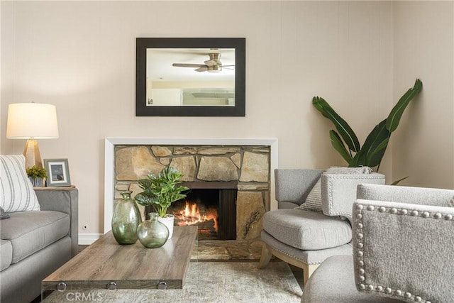 living area featuring ceiling fan and a fireplace