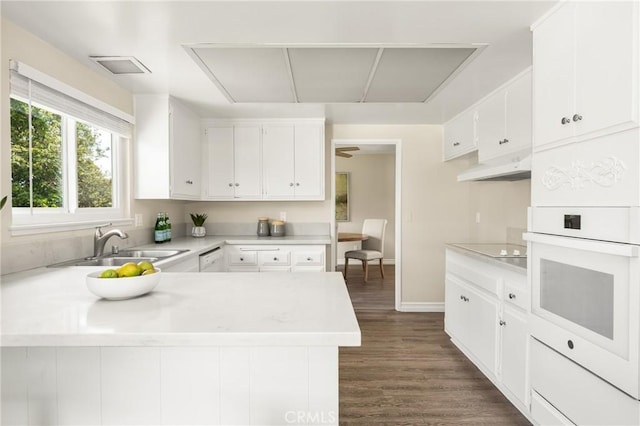 kitchen featuring white cabinetry, sink, dark hardwood / wood-style flooring, kitchen peninsula, and white oven