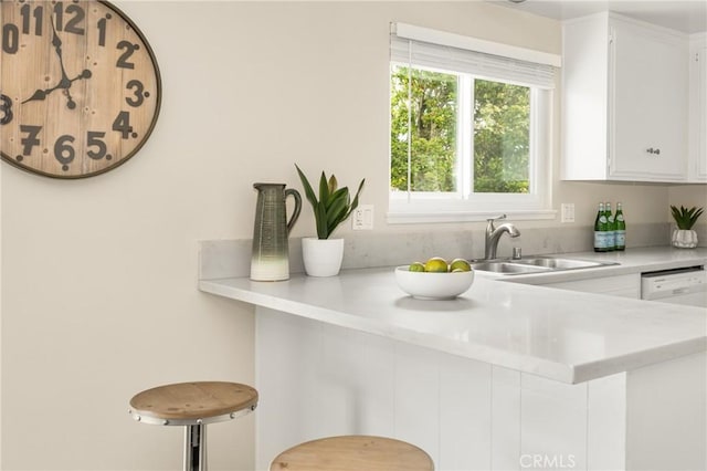 kitchen featuring sink, dishwasher, a kitchen breakfast bar, white cabinets, and kitchen peninsula