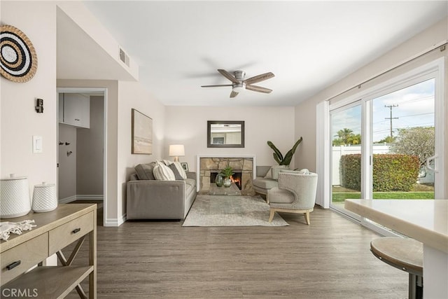 living room featuring ceiling fan, dark hardwood / wood-style floors, and a fireplace