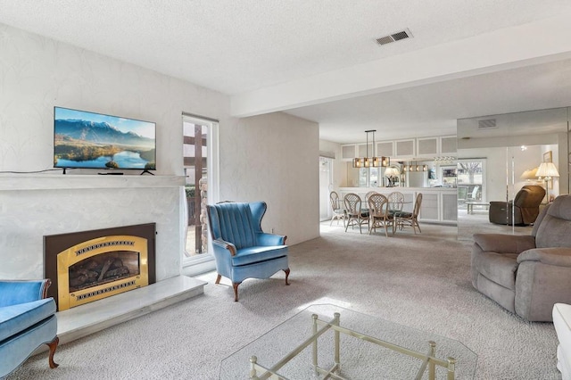 carpeted living room featuring a high end fireplace, beam ceiling, and a textured ceiling